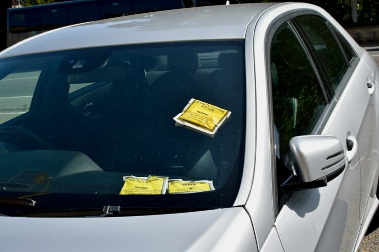 A driver reviews insurance papers and a traffic citation beside car keys at a kitchen table.